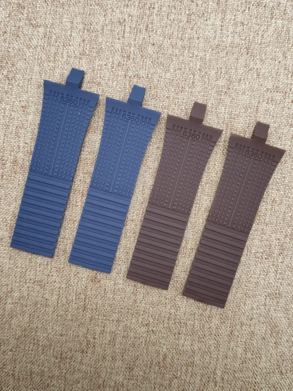 Four rubber strap ends for Porsche Design P6360 in blue and brown, laid on a beige surface.