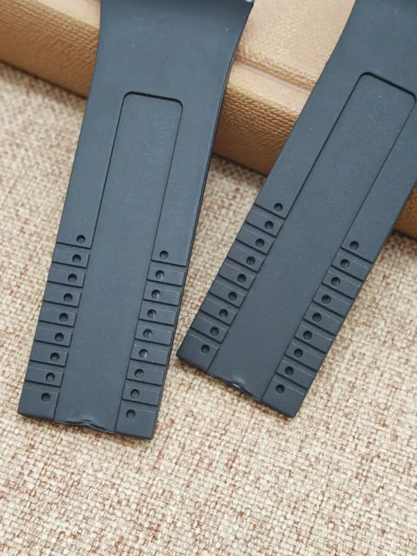 Two black rubber straps for Porsche Design P6780 on a beige fabric surface.