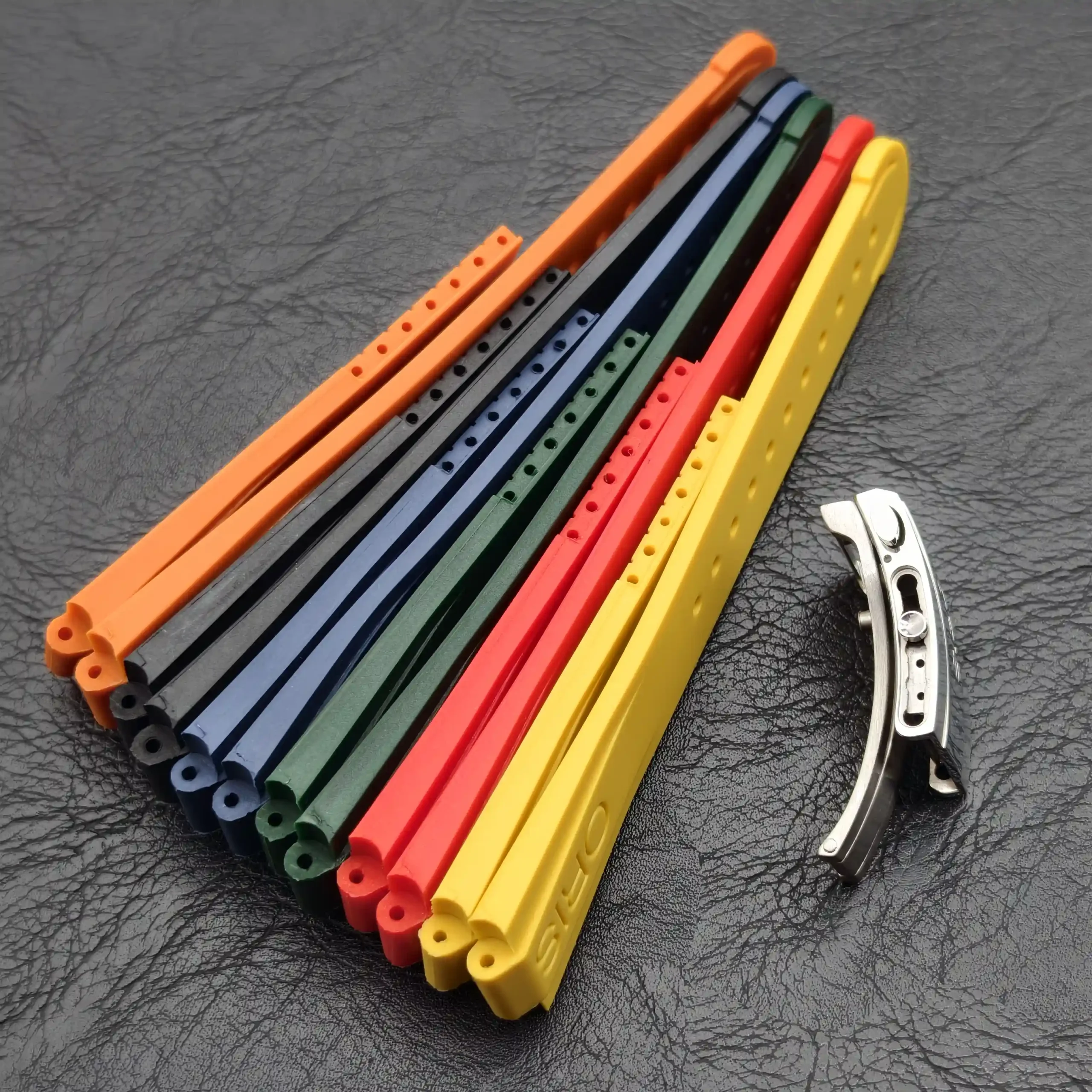 Stack of FKM rubber straps for Oris Aquis in assorted colours, arranged in a curve.