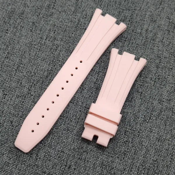 Pale pink silicone watch strap pieces arranged diagonally on a dark gray textured surface.