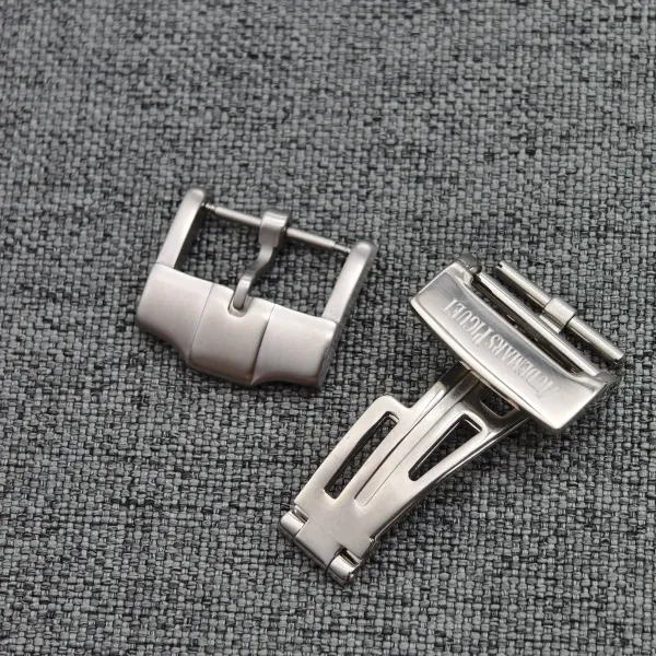 Close-up of a stainless steel watch band with links and buckle on a textured gray fabric background